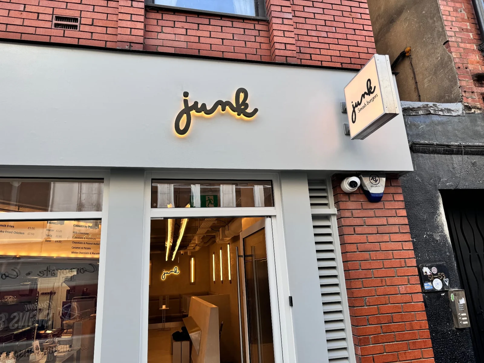 Completed Junk shopfront with halo-lit script lettering on a grey fascia and a matching projecting sign